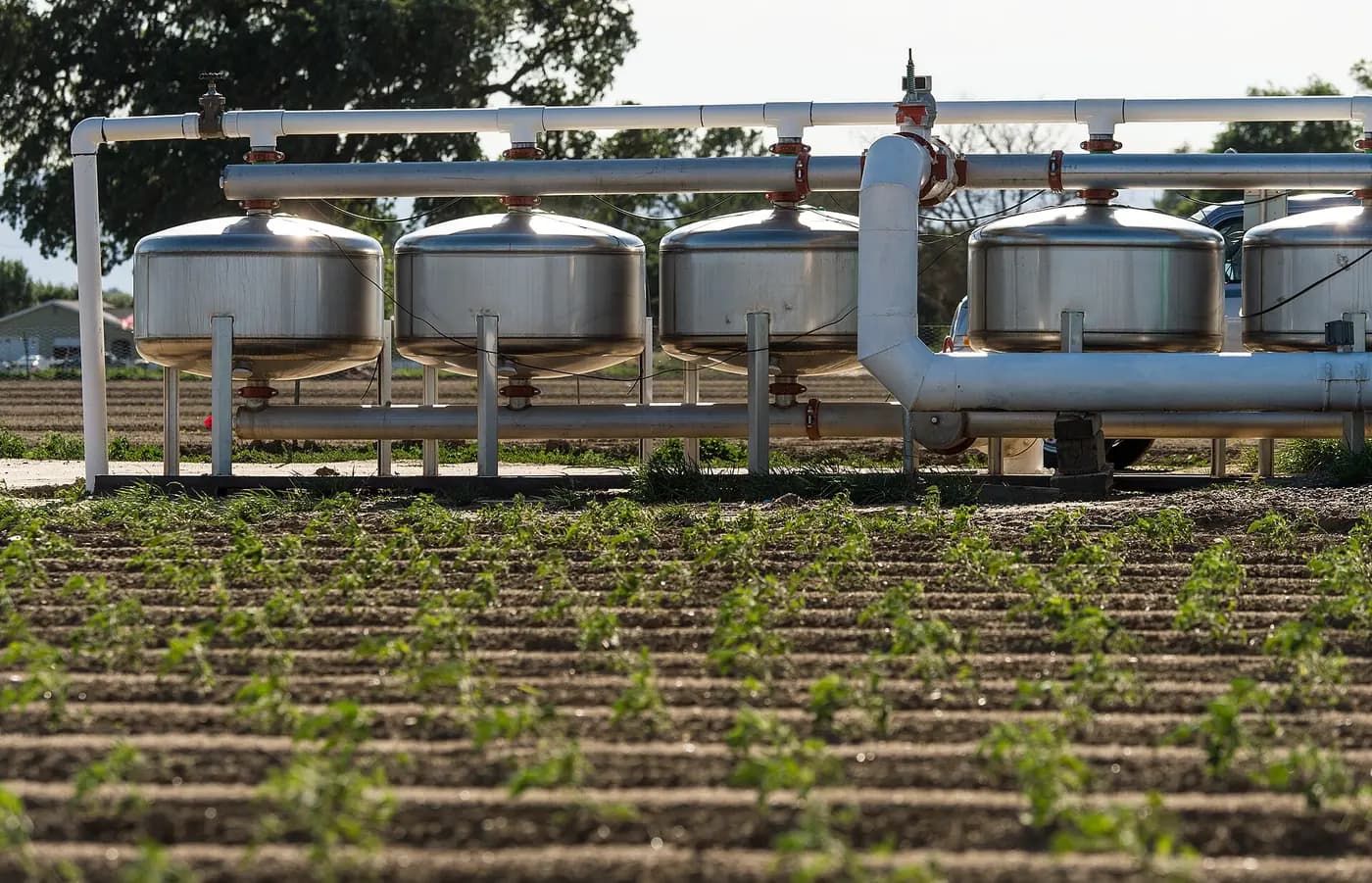 Sand-media filtration vessels and connecting pipes beside crop rows