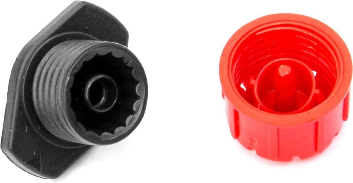 Red adjustable drip emitter separated to show its threaded cap and flow chamber