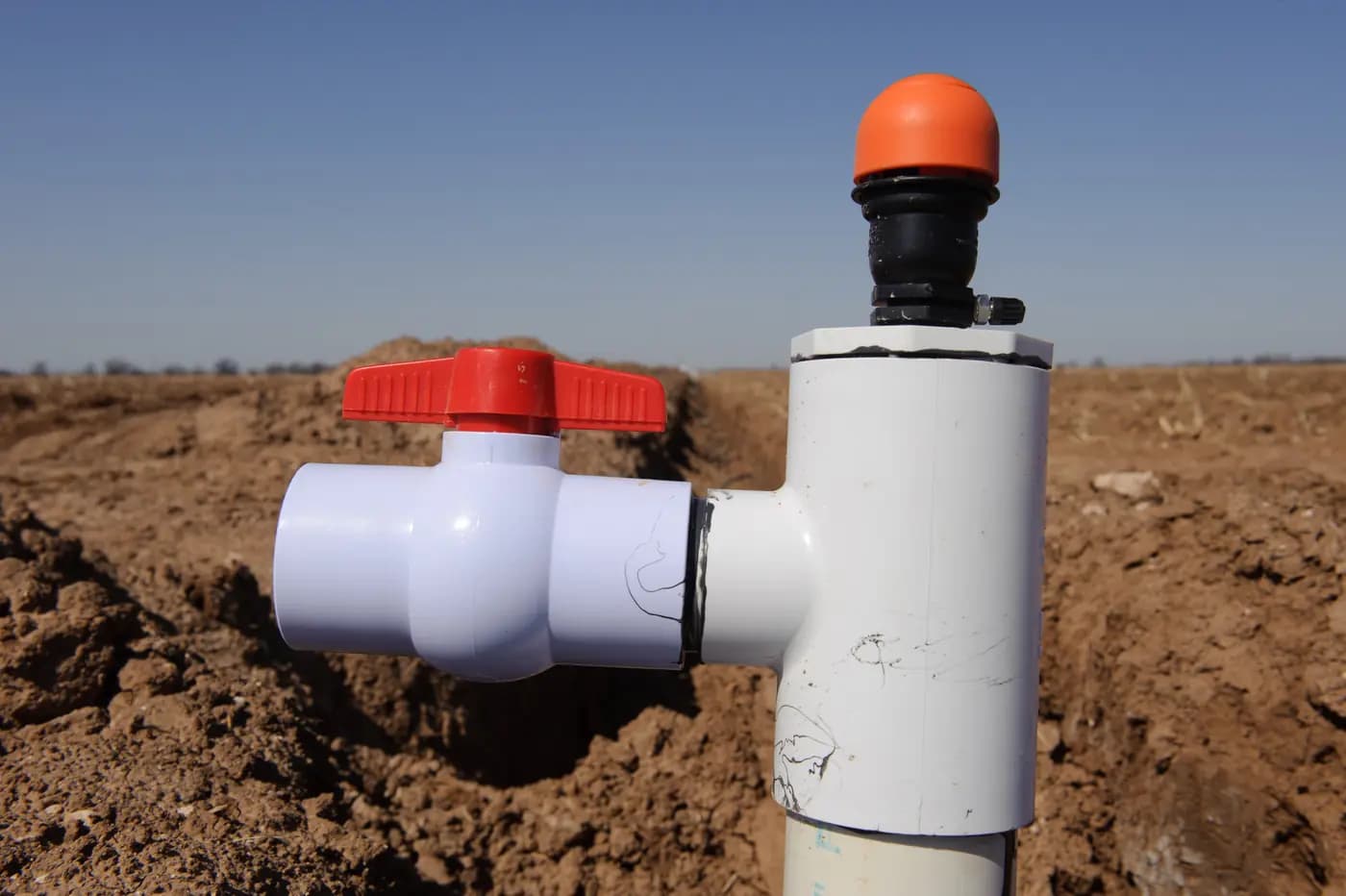 A valve assembly installed on irrigation pipe at the edge of a prepared farm field