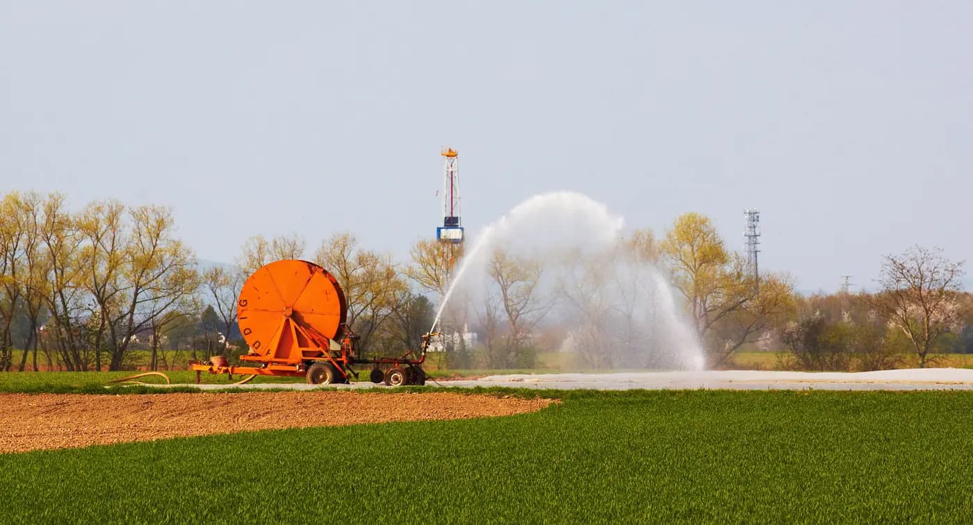A hose-reel irrigation sprinkler spraying a farm field near Herxheim, Germany
